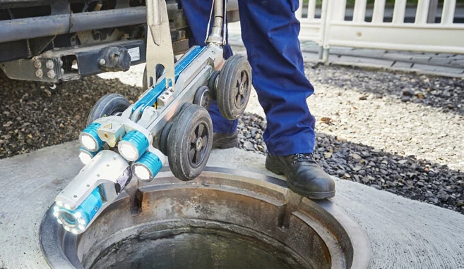 Eine Kalnalkamera wird zur TV-Befahrung von einem Mitarbeiter in den Schacht hinuntergelassen.