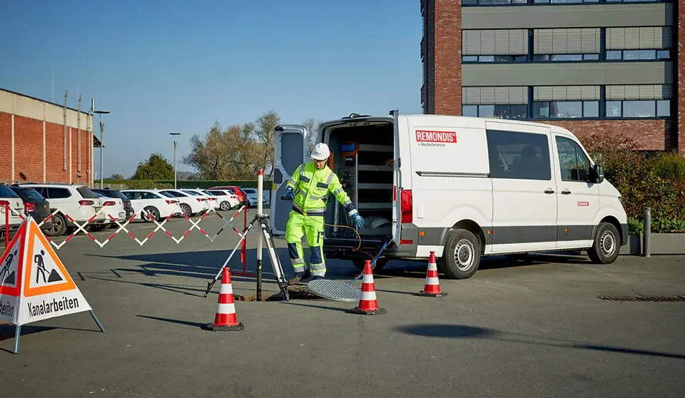 Mitarbeiter von REMONDIS AS-CONTROL richtet hinter dem Prüffahrzeug Messgeräte und Absperrungen für die Abscheiderprüfung ein