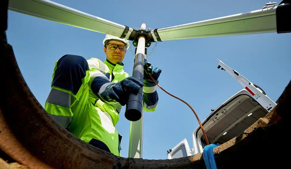 Mitarbeiter richtet einen Dreibock über einem geöffneten Abscheider für Wartungsarbeiten aus