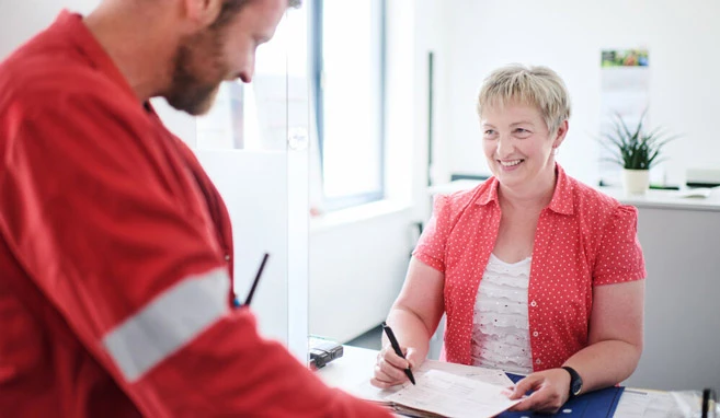 Eine kompetente und herzlich lächelnde Mitarbeiterin füllt mit ihrem Kollegen die Unterlagen zur Übergabe an die Behörden aus.