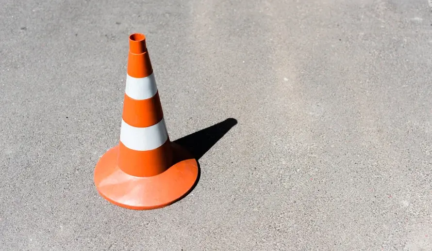 Ein orangefarbener Verkehrskegel steht auf Asphalt.