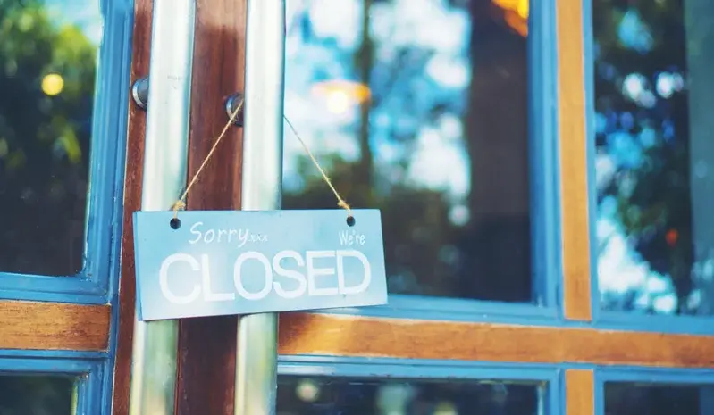 An einer geschlossenen Restaurant-Glastür hängt ein Schild mit dem Text: „Sorry we’re closed.“